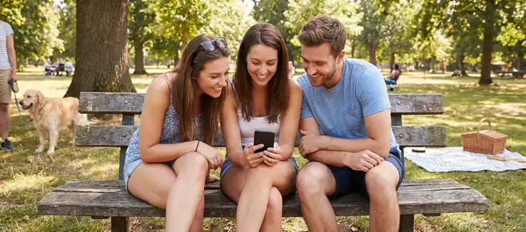 three people gazing at a mobile phone 
