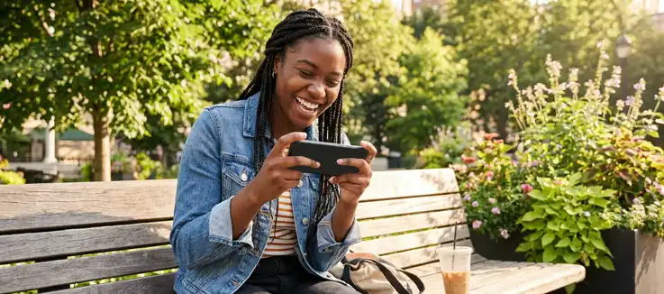young woman enjoying a game on her mobile device while sitting outside in nice weather 